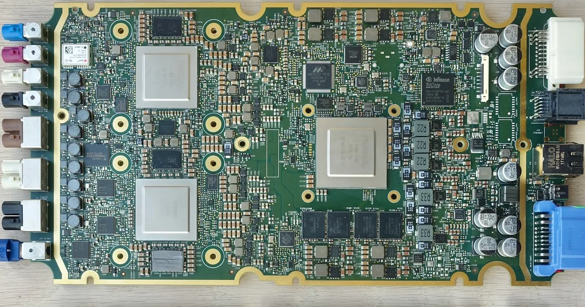 An automotive driver-assistance controller board with two identical processor packages side by side, next to a larger processor, memory, power components and a row of connectors, all on one PCB.